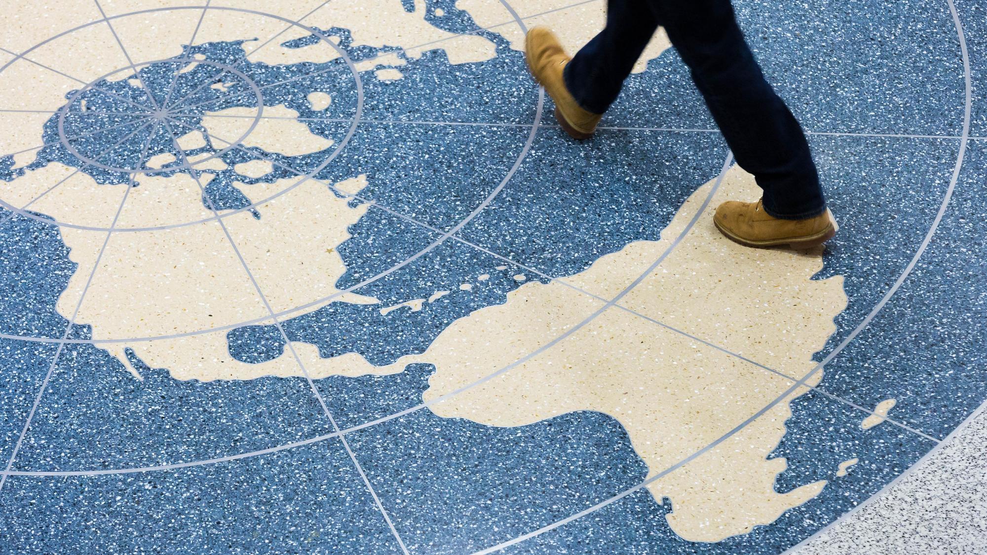 Duques Globe Person walking across image of a globe