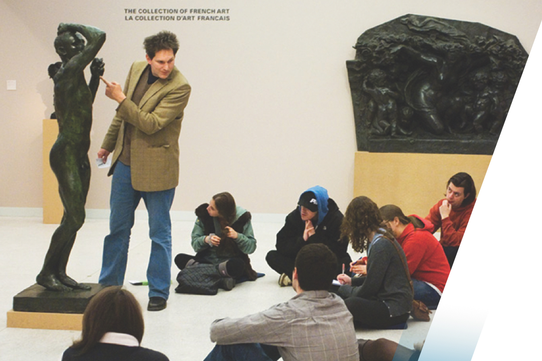 Professor lecturing students with a statute in a museum